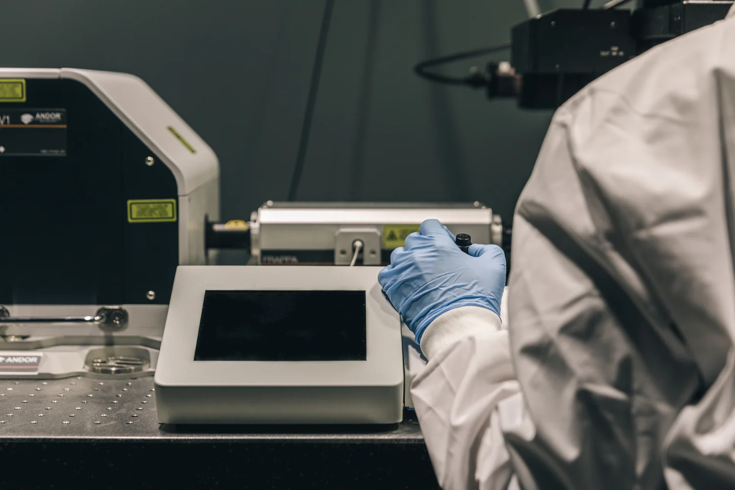 Scientist in white lab coat and blue gloves operating advanced laboratory equipment representing Smart Caffeine science-backed formulation research